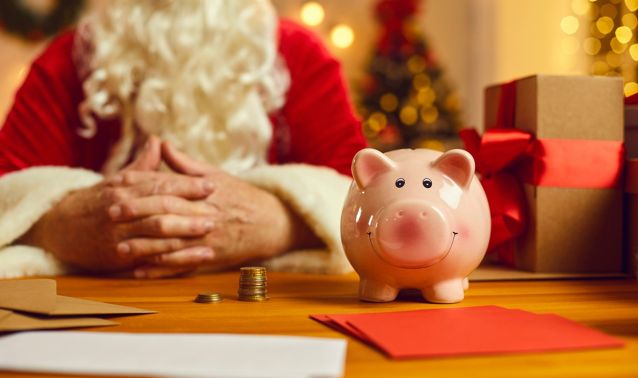 Santa sits by a piggy bank