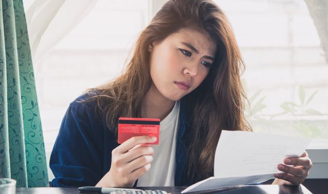 A woman worryingly looks at her bank statement