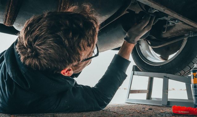 A man working on the underside of a car.