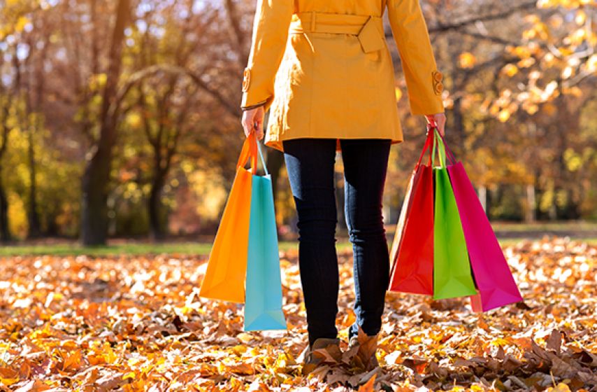 A woman carrying shopping bags in the fall.