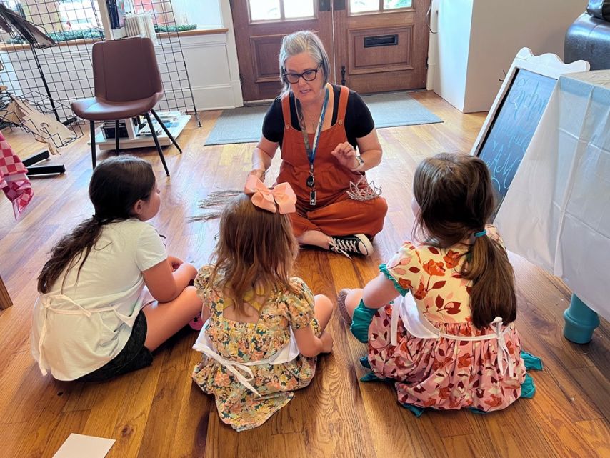 A woman instructs children on how to do art