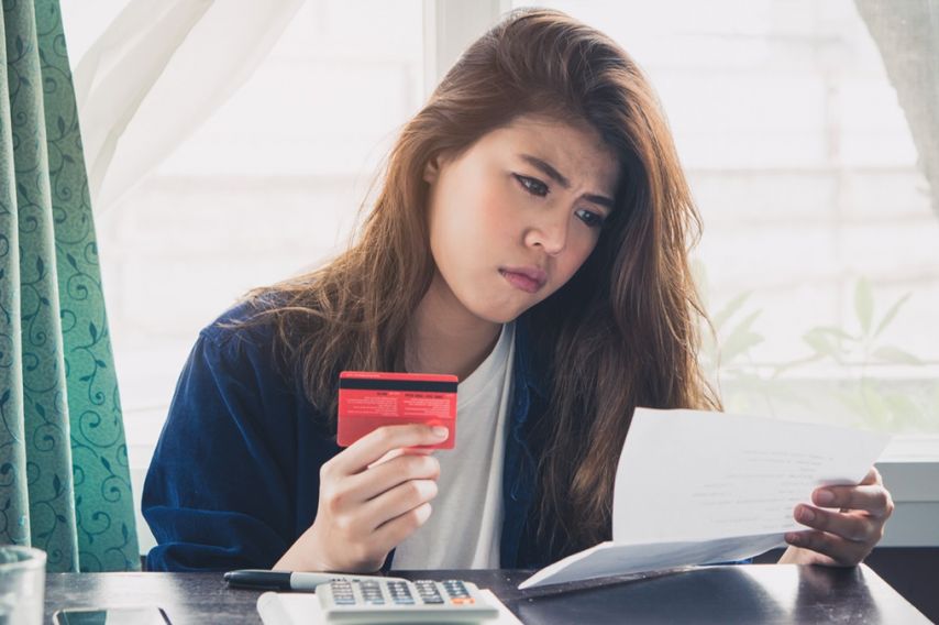 A woman worryingly looks at her bank statement