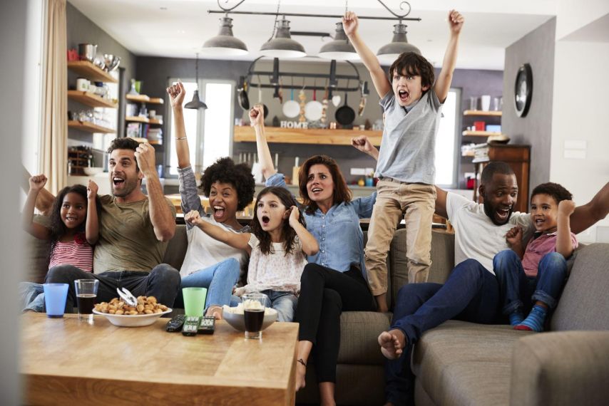 A group gets excited watching sports in their living room.