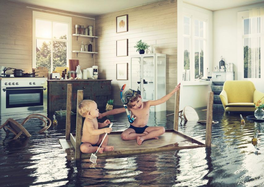 Children floating on their kitchen table in flooded kitchen.