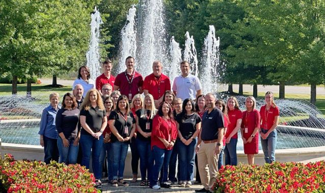 Group of employees stands in front of fountain